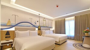 A hotel room with two beds, a nightstand, a lamp, a wall mural, a window with curtains, and a small table with a vase of flowers. - Hotel Sands Point (Puducherry)