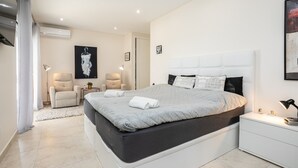A modern bedroom with a large bed, a bedside table, a chair, and a wall-mounted air conditioner. - Charming Villa with Private Pool (4V4) (Altura)