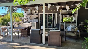 An outdoor patio area with a grill, dining table, and comfortable seating.