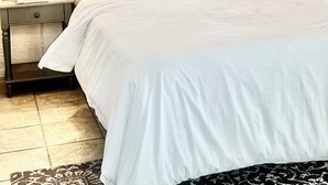 A bedroom with a large bed, two bedside tables with lamps, a wooden wardrobe, and a ceiling fan.
