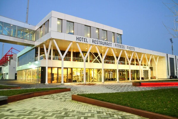 Un hotel moderno con fachada de vidrio, con la leyenda "HOTEL RESTAURANT FITNESS EVENTS".