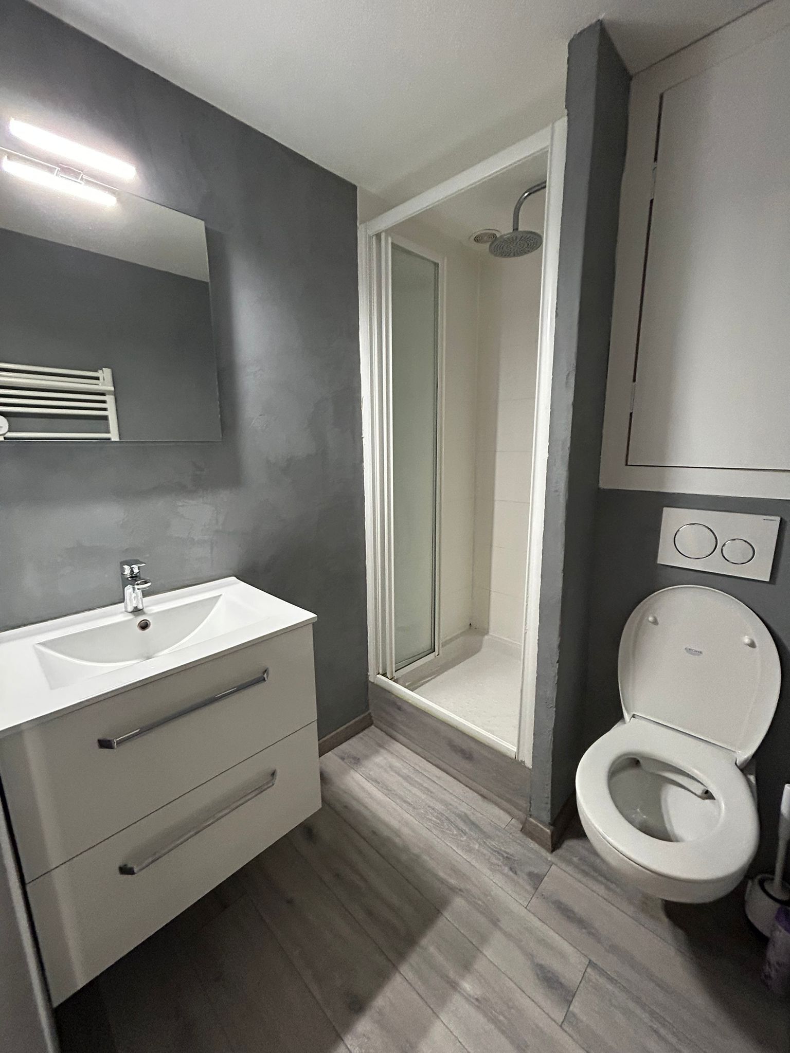 Une salle de bain moderne avec un lavabo blanc, des toilettes et un espace douche.