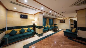 Eine großzügige Lobby mit mehreren Sofas, einem Flachbildfernseher und einem Marmorboden.