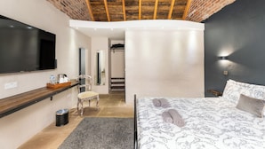 A bedroom with a TV, a bed with rolled towels, a chair, a small table with toiletries, and a staircase leading to another room. - Chapel Farm Hotel (Wellow)