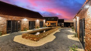 A courtyard with brick buildings, a water feature, and a paved walkway. - Chapel Farm Hotel (Wellow)
