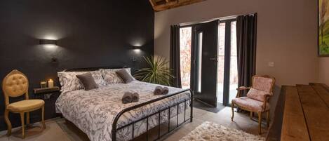 A bedroom with a bed, a chair, a desk, and a plant.