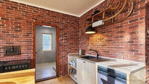 Una cocina con pared de ladrillo, suelo de madera y un lavamanos moderno.