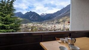En utsikt från en balkong med utsikt över en stad, och berg i bakgrunden.