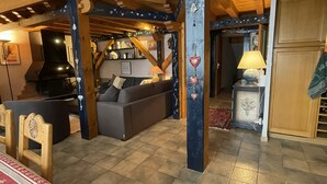 A cozy living room with a sofa, wooden beams, and a fireplace. - Large triplex at the foot of the slopes ideal for two families (Morillon)
