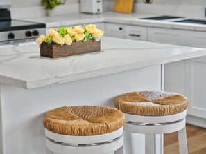 A kitchen with a marble countertop, a wooden flower arrangement, and two wicker stools. - New 2025 Modern Home, Ice-Cold A/C, 8 Min to Sky Harbor, Sleeps 6 (Phoenix)