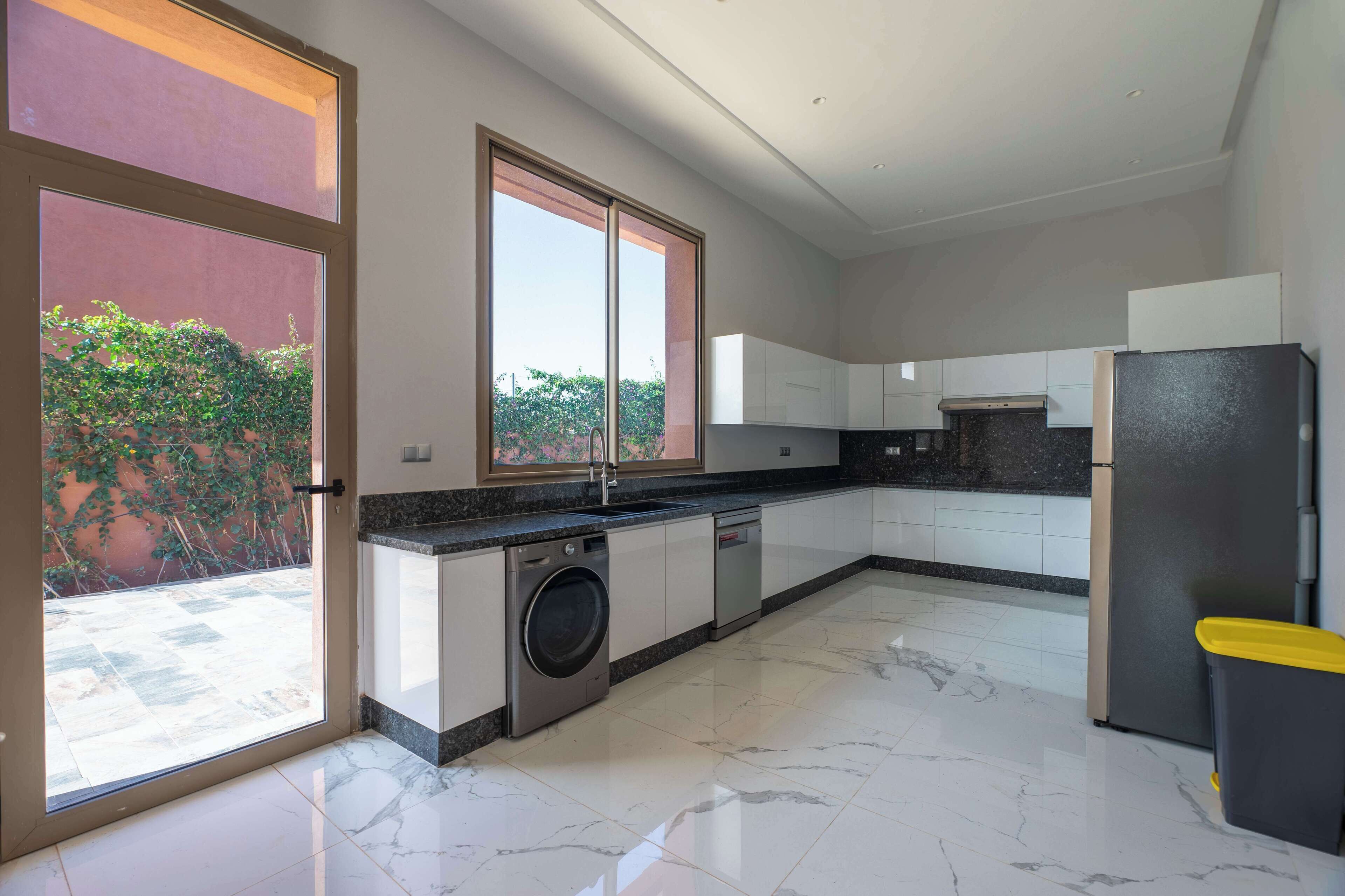 Una cocina moderna con un ventanal grande, lavadora y refrigerador.