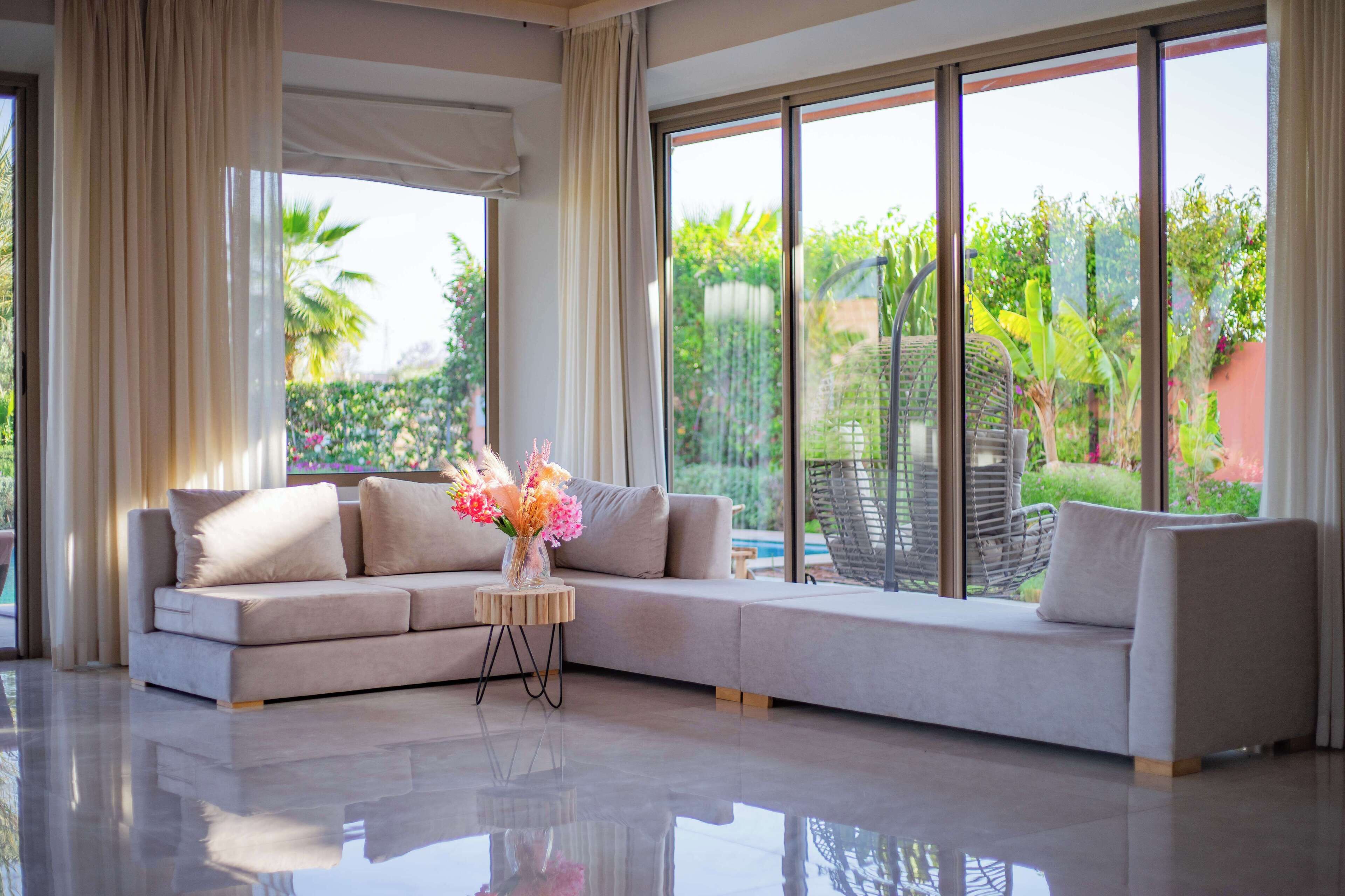 A modern living room with a large window, a sofa, and a small side table with flowers.