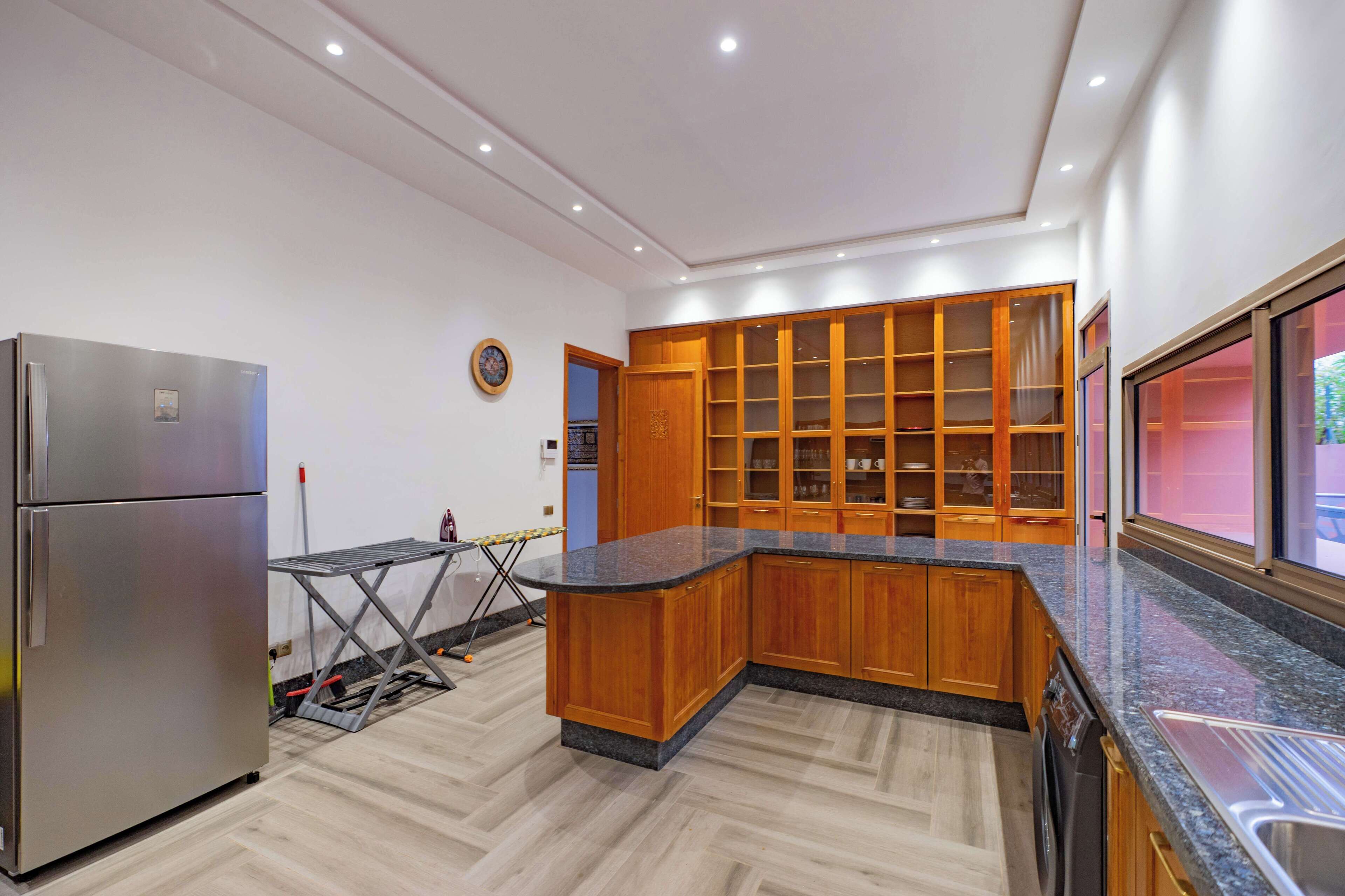 A modern kitchen with wooden cabinets, a stainless steel refrigerator, and a granite countertop.