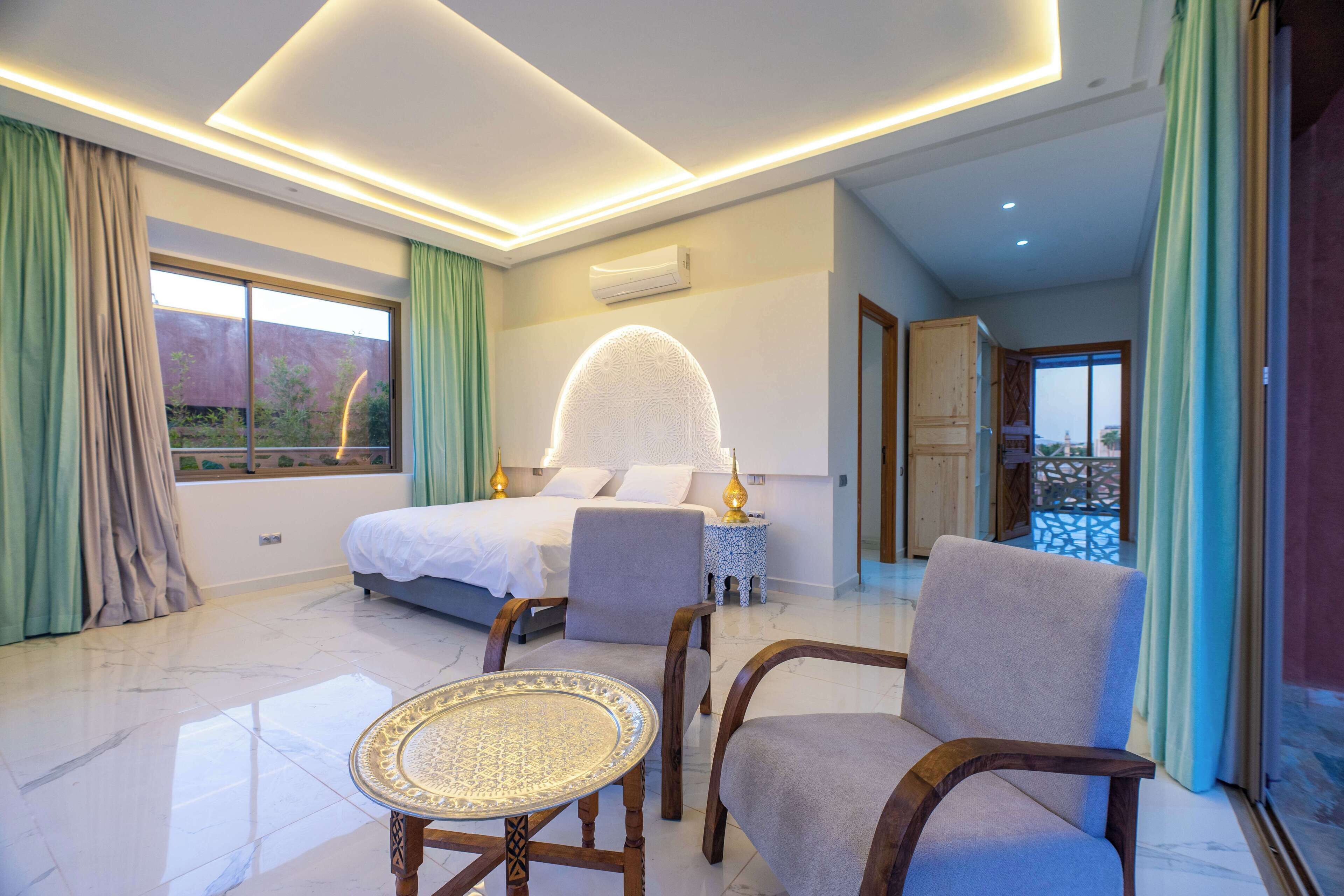 A modern hotel room with a bed, seating area, and a view of the outdoors.
