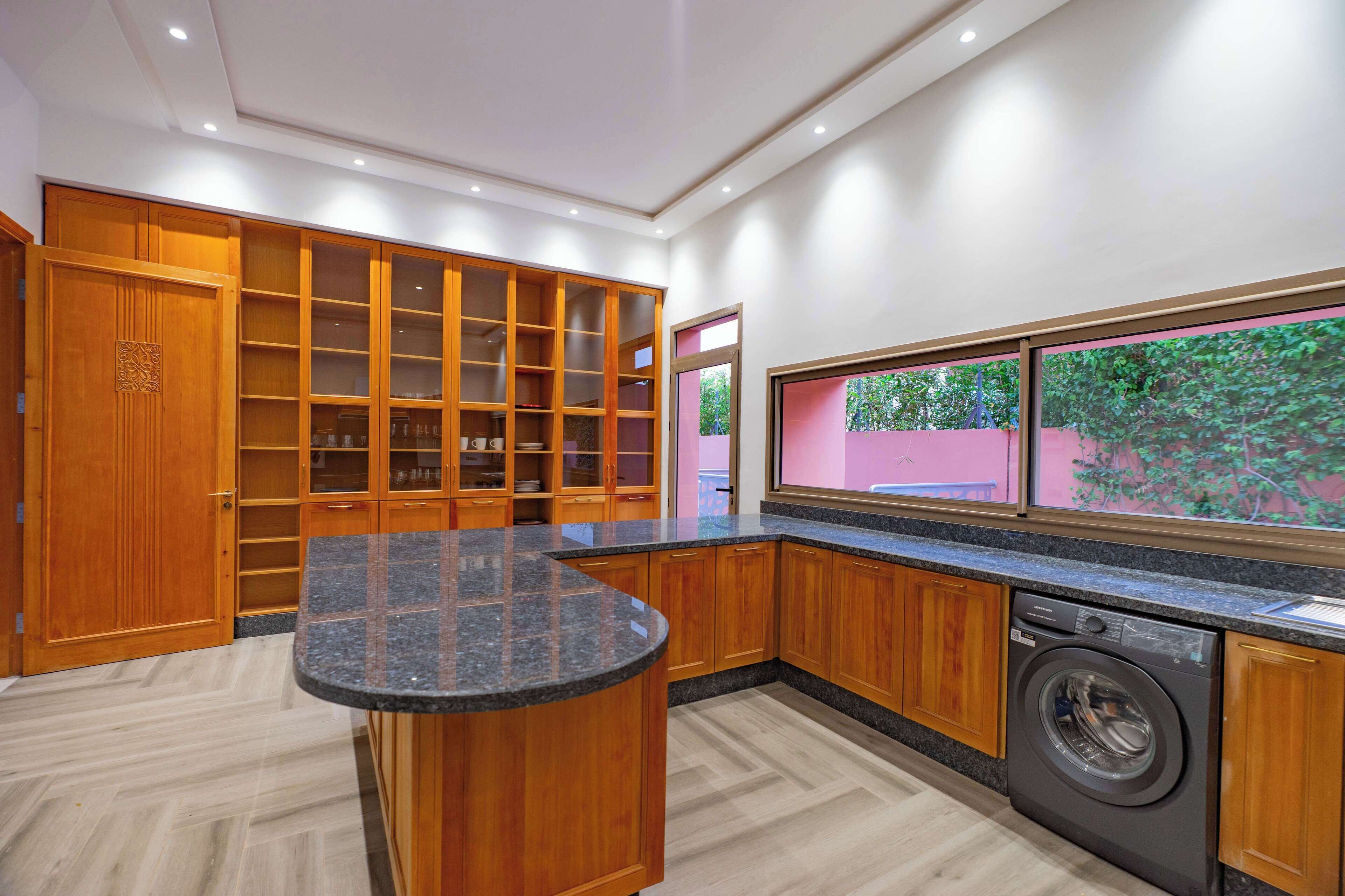 A modern kitchen with wooden cabinets, a granite countertop, and a built-in washing machine.