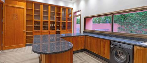 A modern kitchen with wooden cabinets, a granite countertop, and a built-in washing machine.