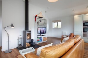 Uma sala de estar moderna com lareira, um sofá de couro, uma televisão e uma cozinha.