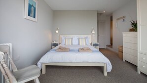 A bedroom with a bed, bedside tables, a chair, a dresser, and a painting on the wall. - Sloopside - Bantham, South Devon (Bantham)