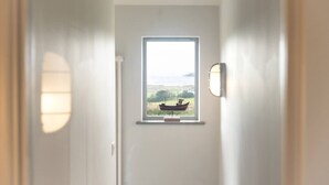 A hallway with a window leading to a view of a boat on water. - Sloopside - Bantham, South Devon (Bantham)