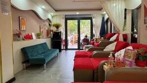 A hotel lobby with a teal sofa, red-covered couches, and a reception desk. - Came House - Near Bui Vien street (Ho Chi Minh City)