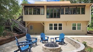 A two-story house with a deck, outdoor seating, and a fire pit. - Sandstorm-New '26, Pet Friendly Home with Outdoor Space (Pawleys Island)