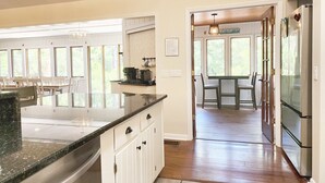 A kitchen with a large island, white cabinets, and a dining area with a table and chairs. - Sandstorm-New '26, Pet Friendly Home with Outdoor Space (Pawleys Island)