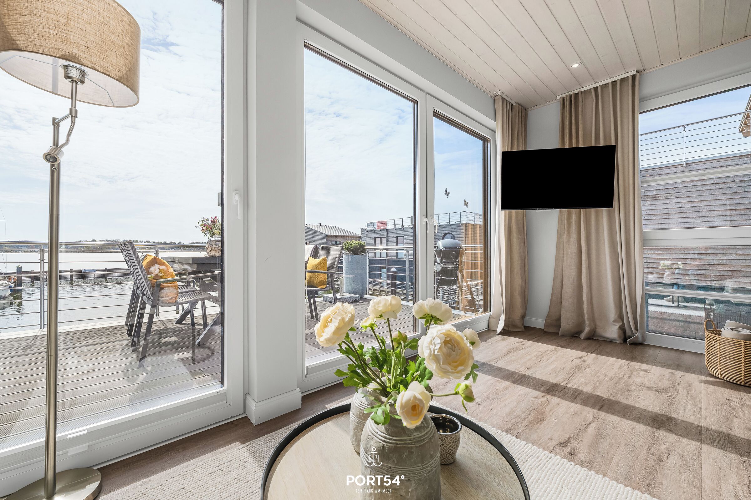 A modern room with large windows, a flat-screen TV, and a view of the cityscape.