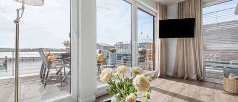 A modern room with large windows, a flat-screen TV, and a view of the cityscape.