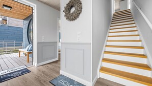 Una escalera con escalones de madera, pared blanca y techo de madera.