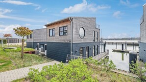 Un edificio moderno de dos pisos con techo plano, ventanas amplias y un tragaluz circular.