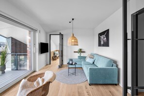 Una sala de estar moderna con un sofá, una lámpara colgante y un televisor.