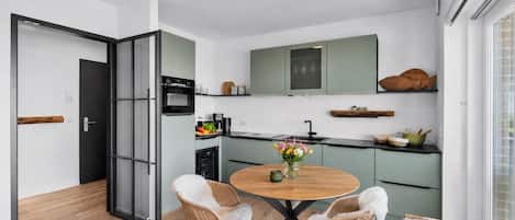 Une cuisine moderne avec un coin repas, comprenant une table ronde, deux chaises et un vase de fleurs.