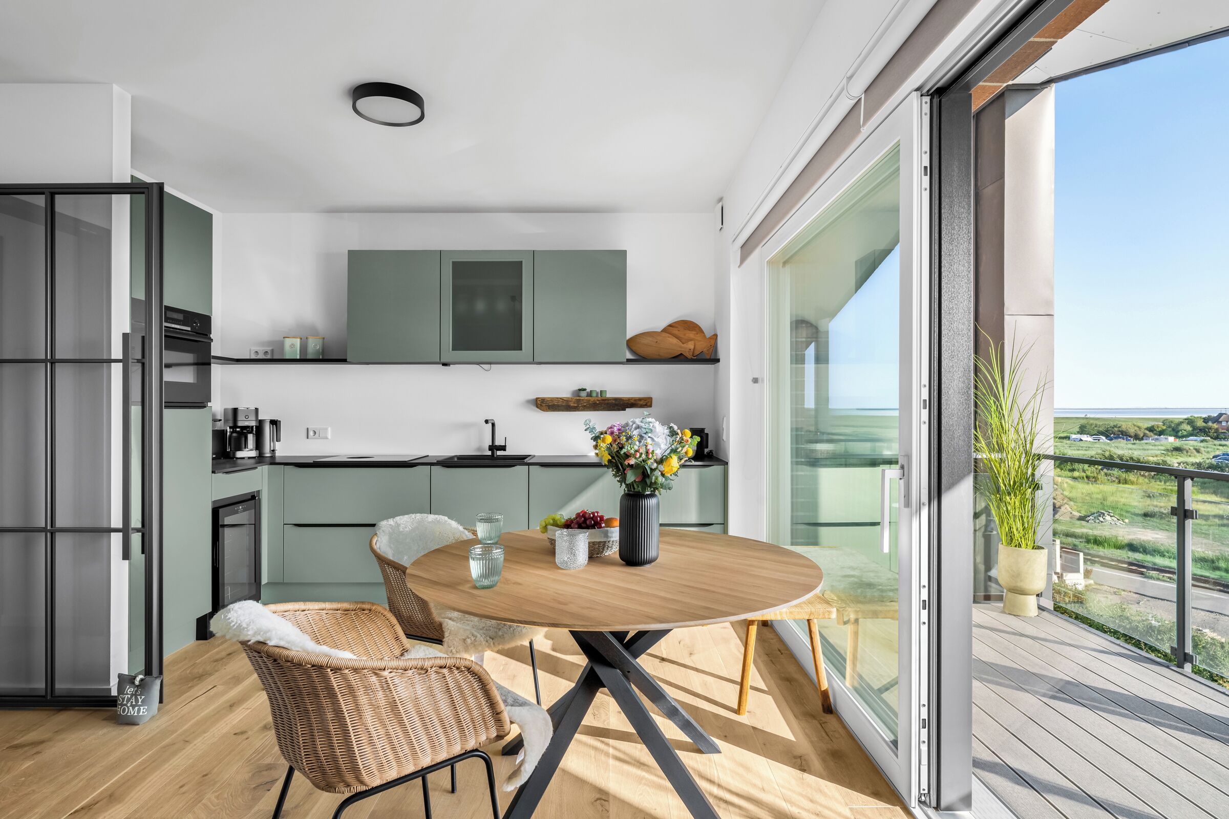 Een moderne keuken met een eetgedeelte, uitzicht op de omgeving en een balkon.