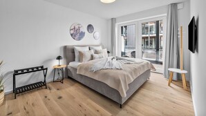 A modern bedroom with a bed, bedside tables, a standing lamp, and artwork on the wall. - The View B08 Kapitänskajüte - Elevator, shared Sauna, underfloor heating,balcony (Dagebüll)