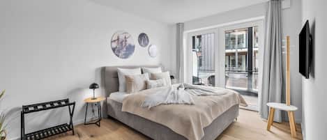 Ein modernes Schlafzimmer mit Bett, Nachttischen, einer Stehlampe und Kunstwerken an der Wand.