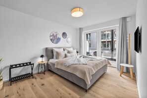 Ein modernes Schlafzimmer mit Bett, Nachttischen, einer Stehlampe und Kunstwerken an der Wand.