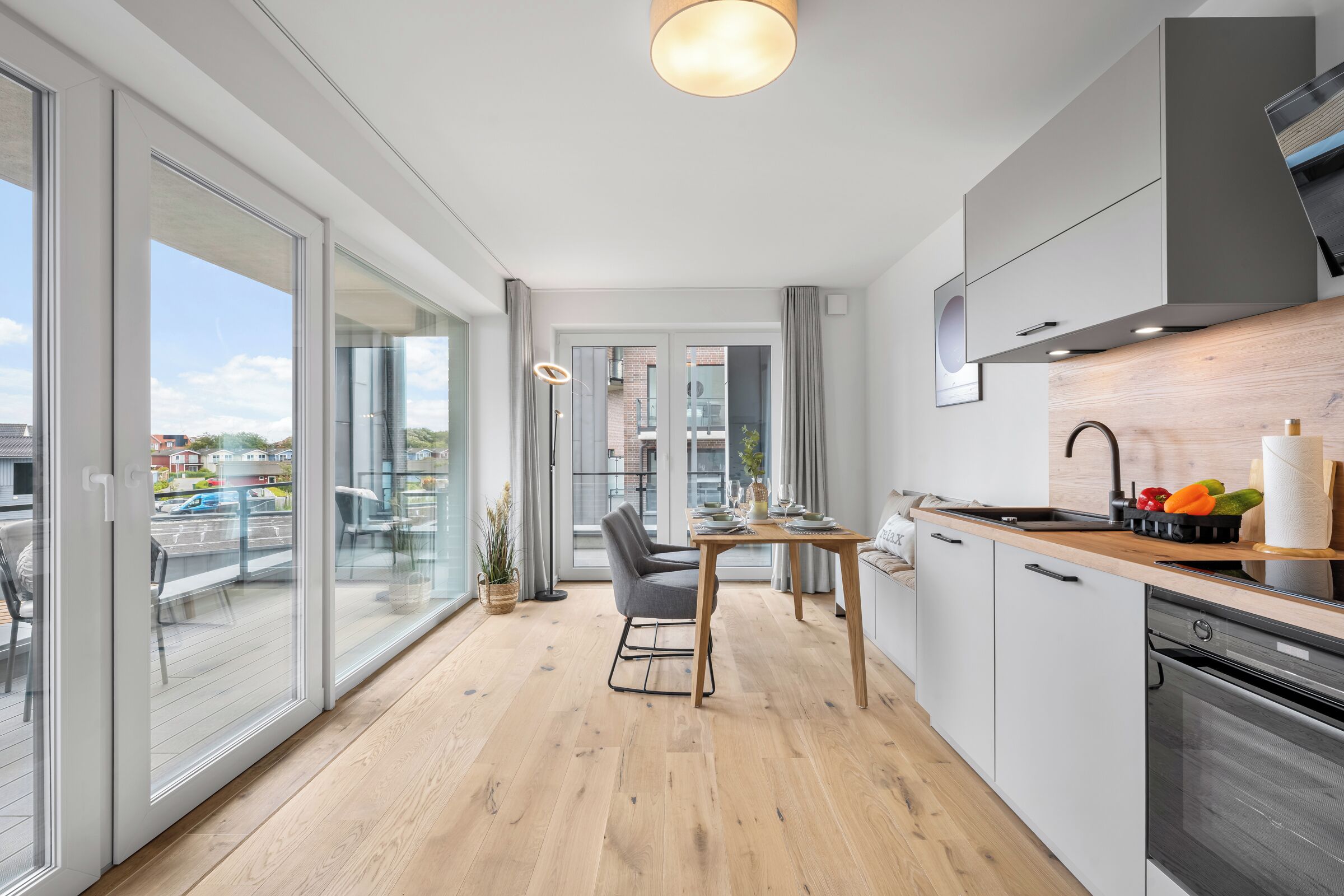 Een moderne keuken met een eethoek, grote ramen en stadszicht.