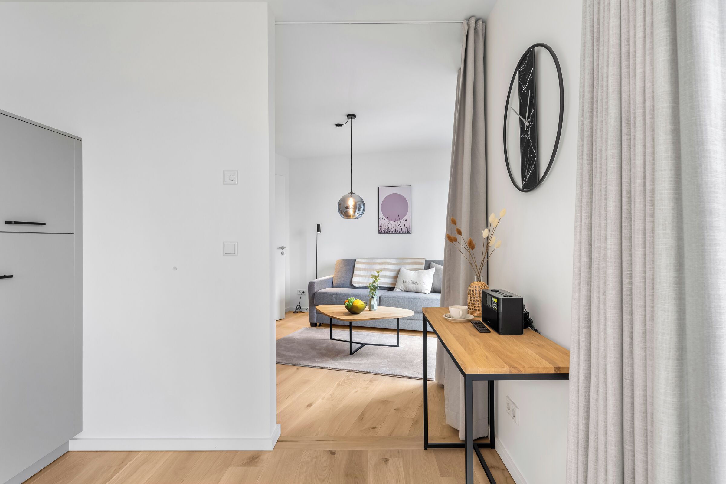 En moderne stue med sofa, sofabord og spiseområde med bord og stole.
