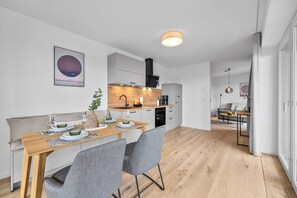 Una cuina moderna amb taulell de fusta, electrodomèstics integrats i vista a la zona de dinar.