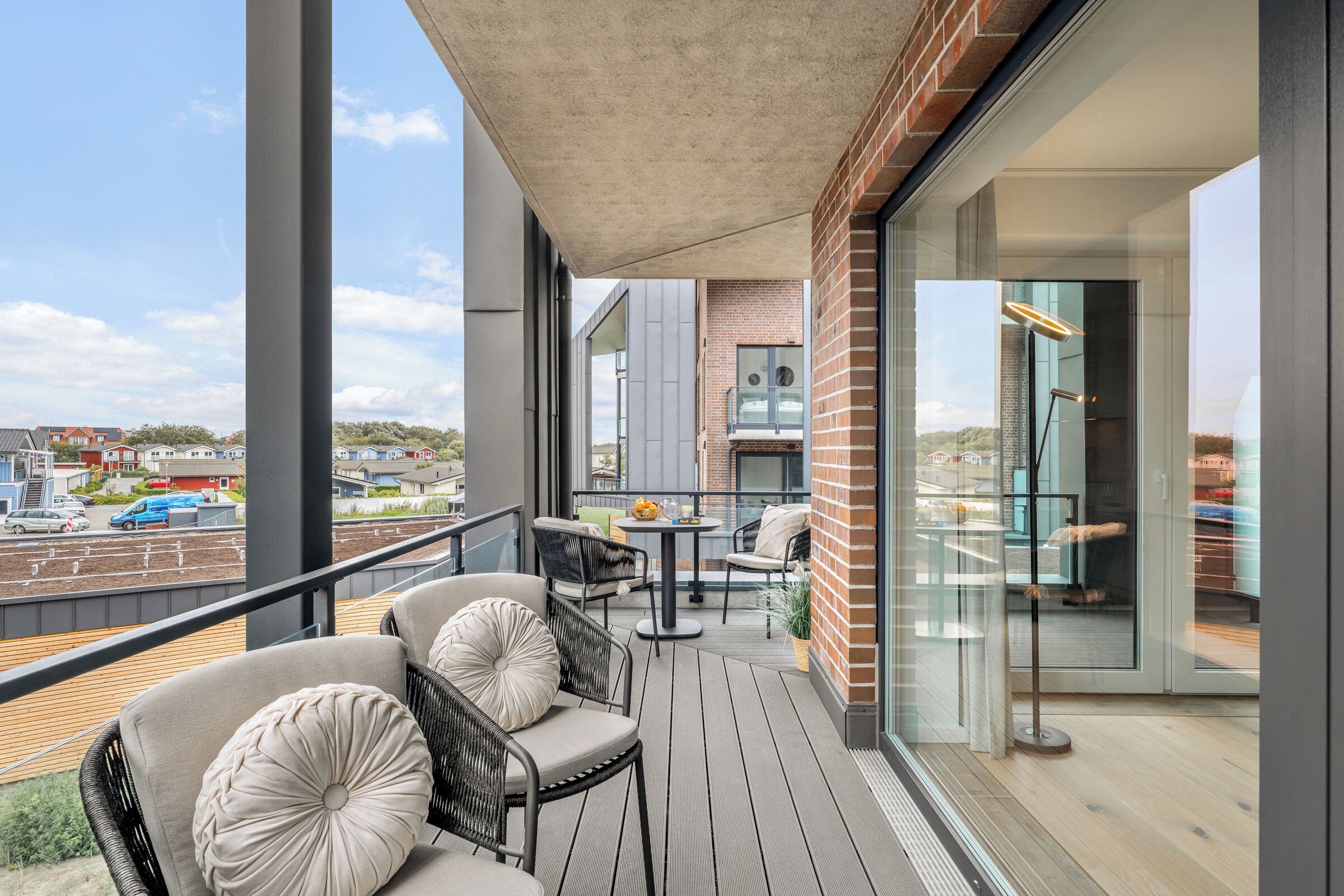 A balcony with outdoor seating, a table, and a view of the surrounding area.