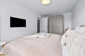 A modern bedroom with a large bed, a flat-screen TV mounted on the wall, and a wardrobe with sliding doors. - The View B08 Kapitänskajüte - Elevator, shared Sauna, underfloor heating,balcony (Dagebüll)