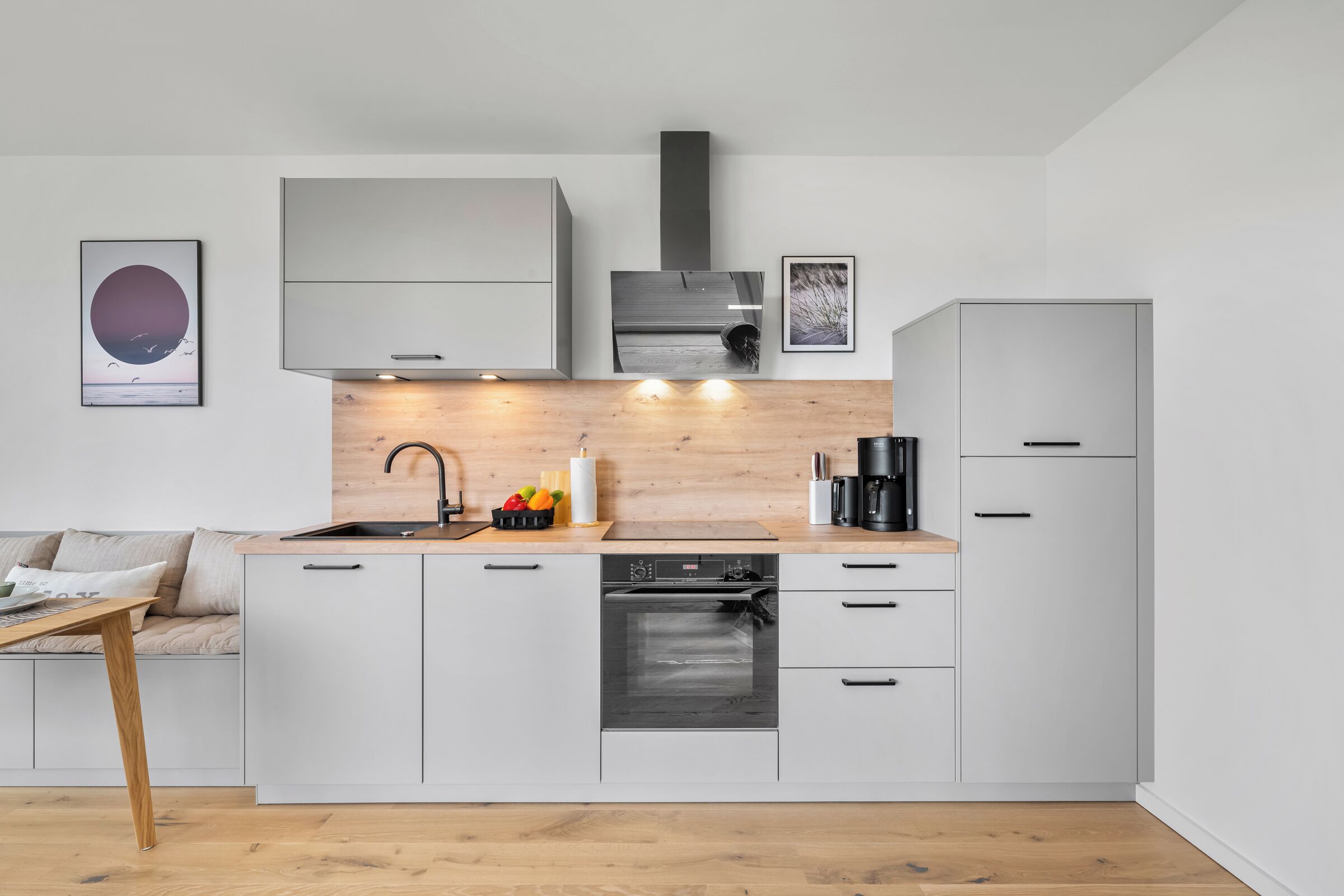 A modern kitchen with white cabinetry, a wooden countertop, a built-in oven, and a coffee machine.