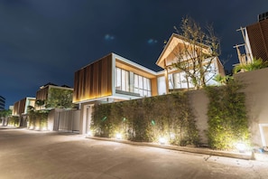 A modern residential building with large windows and a well-lit exterior at night. - Brand New 3Br Elite Pool Villa V293 (Choeng Thale)