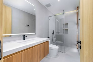 A modern bathroom with a large mirror, two sinks, a toilet, and a glass-enclosed shower area. - Brand New 3Br Elite Pool Villa V293 (Choeng Thale)