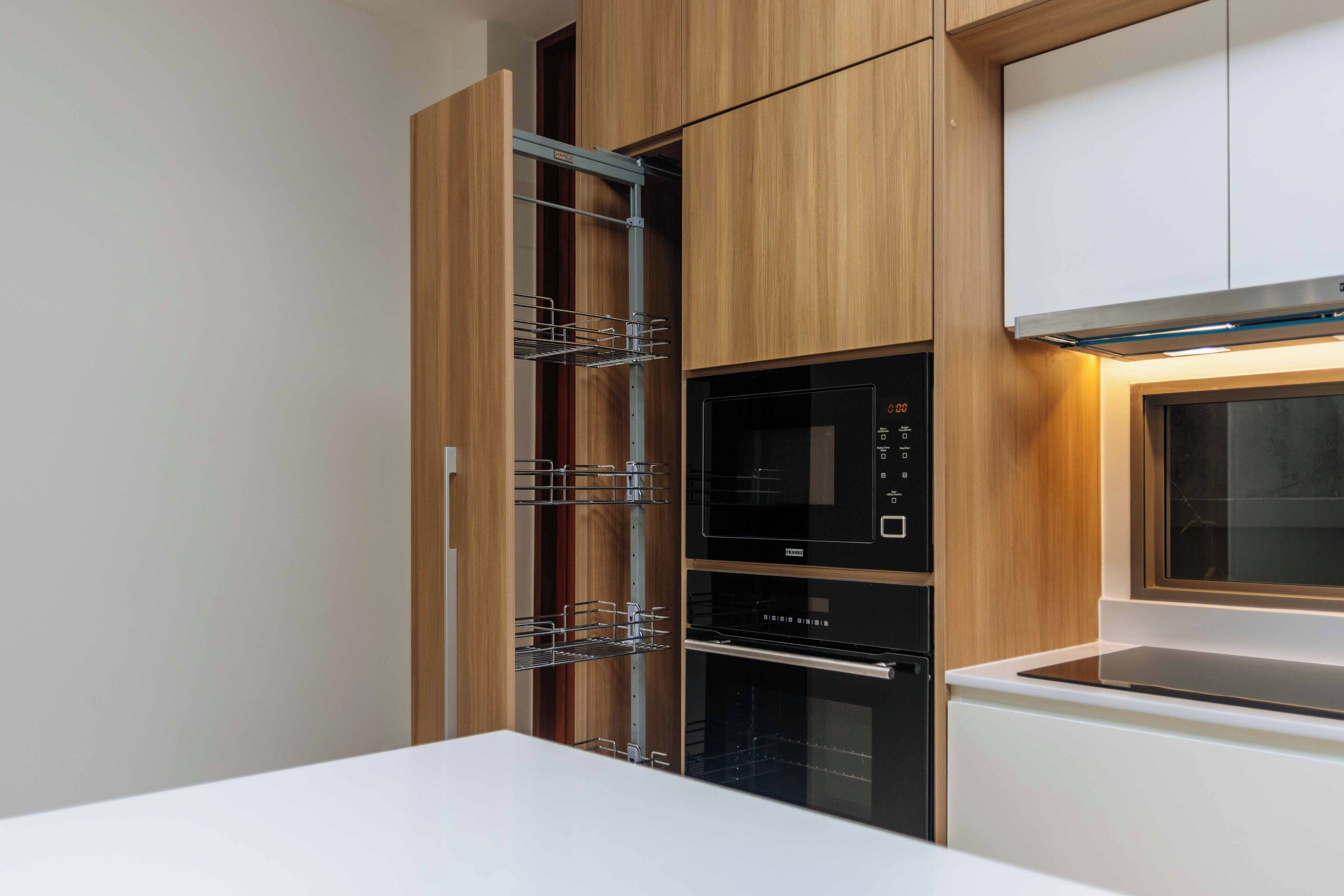 Una cocina moderna con electrodomésticos integrados, incluyendo un microondas, horno y una vinoteca incorporada a los armarios.