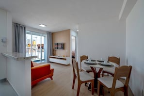 Una cocina moderna con comedor, televisor y balcón con cortinas.