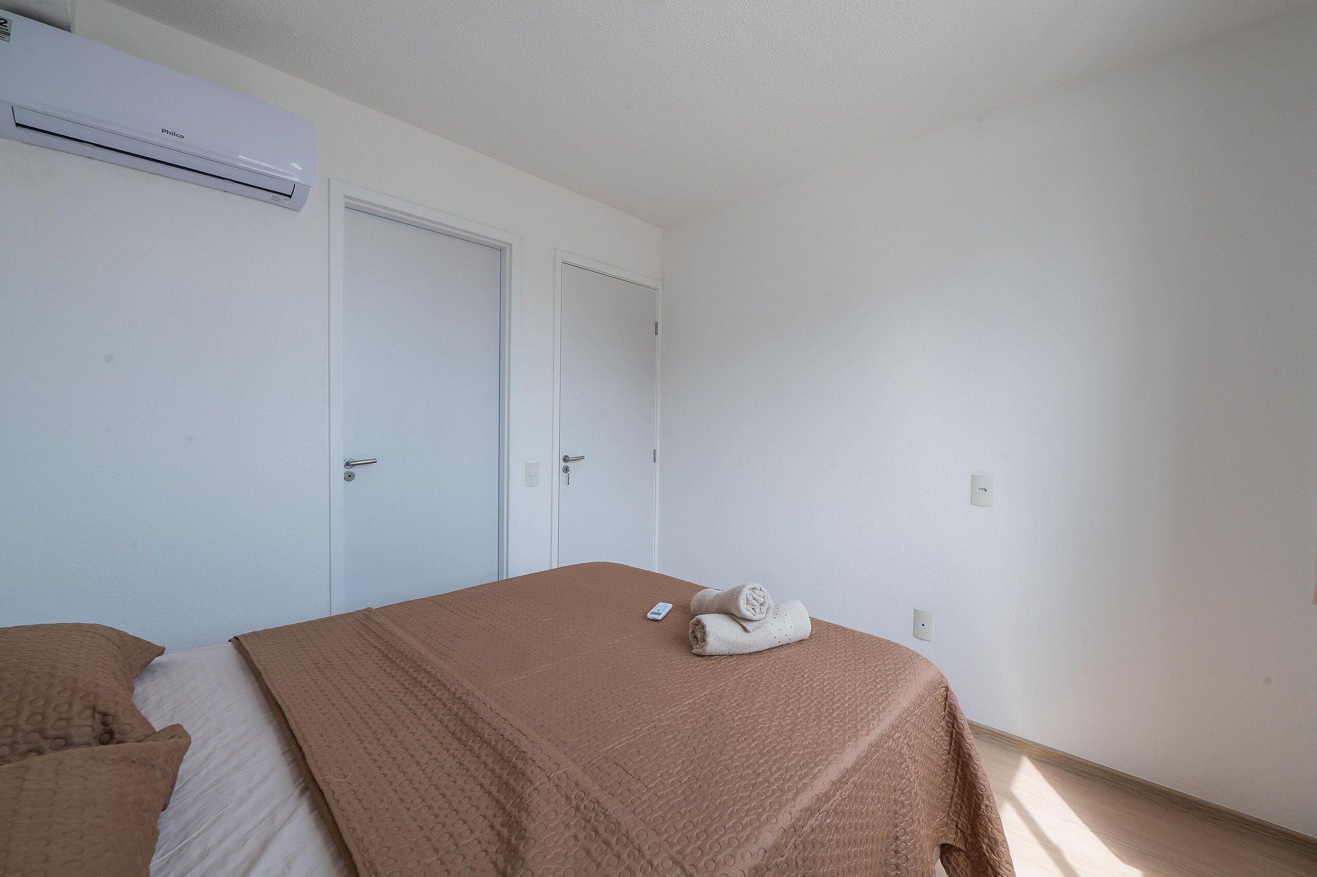 Ett hotellrum med en säng, en garderob och en luftkonditioneringsanläggning.