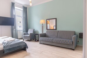 A hotel room with a bed, a sofa, a chair, a lamp, and a TV. - Comfy Room Long Stay Near Belvedere (Vienna)