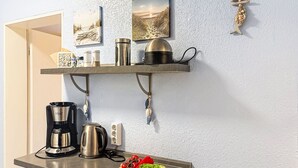 Un piano di lavoro in cucina con una macchina del caffè, un bollitore e verdure fresche.