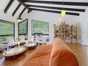 A modern living room with large windows, a bookshelf, and a sofa.